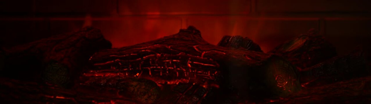 Close up of artificial fireplace logs glowing providing warmth and a cozy inviting atmosphere inside a home.