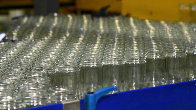 A conveyor belt with neat rows of glass jars