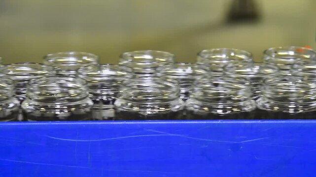 A conveyor belt with neat rows of glass jars