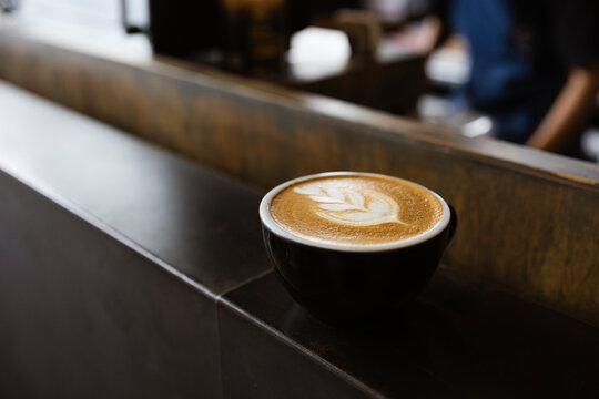 Latte Art Coffee Cup on Cafe Counter with Warm Morning Light and Copy Space