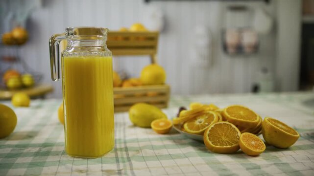 Pitcher of juice next to orange slices on kitchen counter - medium, tracking shot