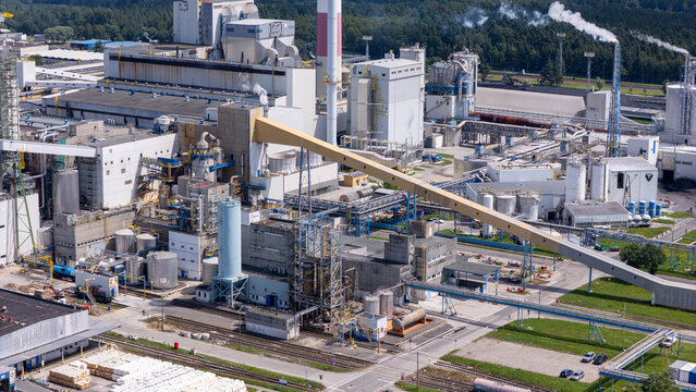 Aerial view of a large industrial paper mill facility with tall chimneys, complex piping systems, and conveyor belts in Grudziadz, Kuyavian-Pomeranian, Poland.