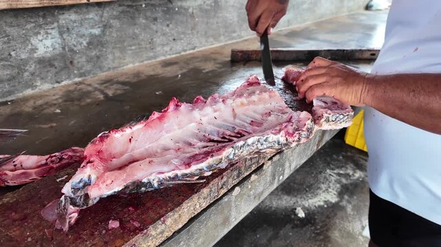 Close-up of hands expertly scraping remaining meat from a fish spine, highlighting sustainable fishing practices and traditional manual food preparation.