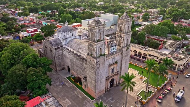 Aerial view of the San Gervasio Cathedral in Valladolid, Mexico, the twin-towered colonial stone facade rising above the plaza and historic streets.