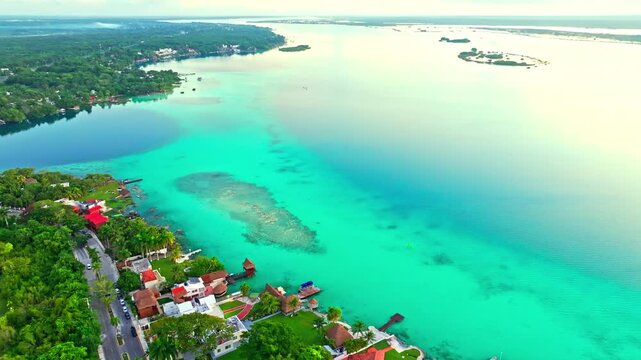Aerial view of a submerged reef in the turquoise Bacalar lagoon, Mexico, emerald shoals glowing beneath the water beside the lakeside town.