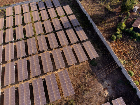 Aerial view of a solar farm with rows of photovoltaic panels installed in an arid field, surrounded by a perimeter fence in Loitokitok, Kajiado County, Kenya.