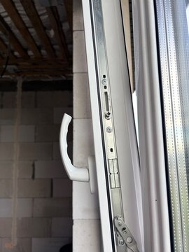 A PVC window frame with metal locking mechanism. Window installation and building renovation