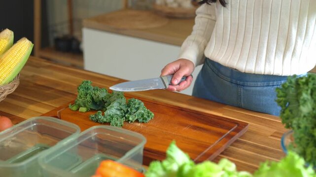 Woman Chopping Fresh Kale on Wooden Cutting Board for Healthy Meal Prep in Modern Kitchen