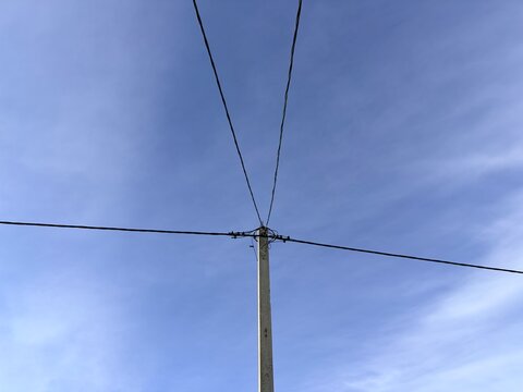Power lines stretching across a blue sky. Concepts of energy, infrastructure, and rural or suburban landscapes