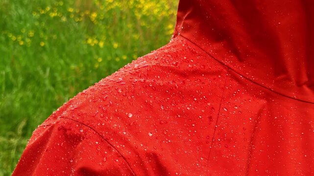 Camera pans slowly across hiker orange rain jacket covered in mist and water droplets in Flam Aurland Norway