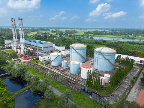 Aerial view of Santahar Power Plant with large industrial storage tanks, tall chimneys, and surrounding lush greenery in Santahar Pouroshova, Rajshahi Division, Bangladesh.