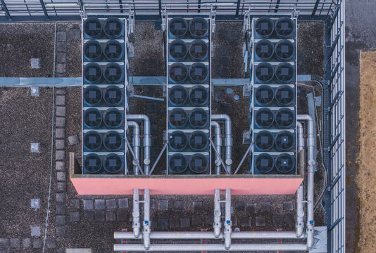 Aerial view of industrial rooftop cooling infrastructure featuring rows of dry coolers, HVAC systems, and mechanical piping for thermal management Valence, Auvergne-Rhone-Alpes, France.