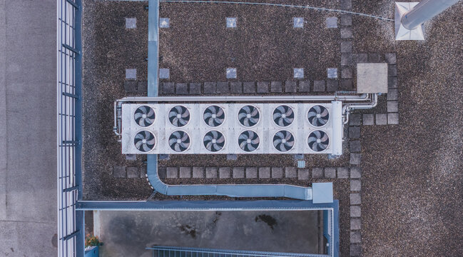 Aerial view of an industrial dry cooler on a rooftop featuring multiple axial fans, insulated piping, and ventilation ductwork in Valence, Auvergne-Rhone-Alpes, France.