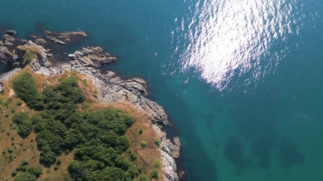 Aerial Top-Down View of Rocky Coastline and Deep Blue Sea Water