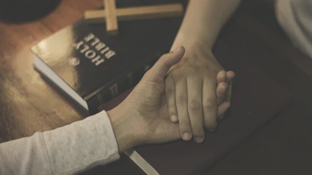 Two people holding hands and praying together, expressing faith, worship, devotion, hope, peace, and spiritual connection.