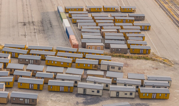 Aerial view of rows of prefabricated modular homes and tiny houses at a manufacturing facility, showcasing modern factory-built housing in Valence, Auvergne-Rhone-Alpes, France.