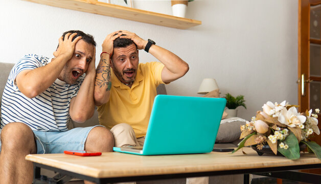 Two men reacting with shock and disbelief watching laptop