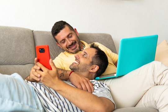 Gay couple in love relaxing on the sofa and looking at each other.
