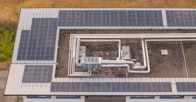 Aerial view of rooftop solar panels integrated with industrial HVAC equipment and process piping at a manufacturing facility in Valence, Auvergne-Rhone-Alpes, France.
