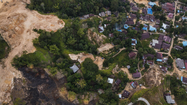 Aerial view of a rural village nestled among lush tropical vegetation and areas of cleared land in Papua, Indonesia.