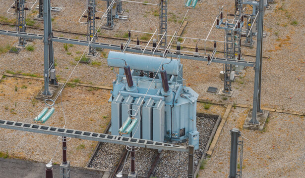 Aerial view of a high-voltage electrical transformer and switching equipment inside a modern power substation in Valence, Auvergne-Rhone-Alpes, France.