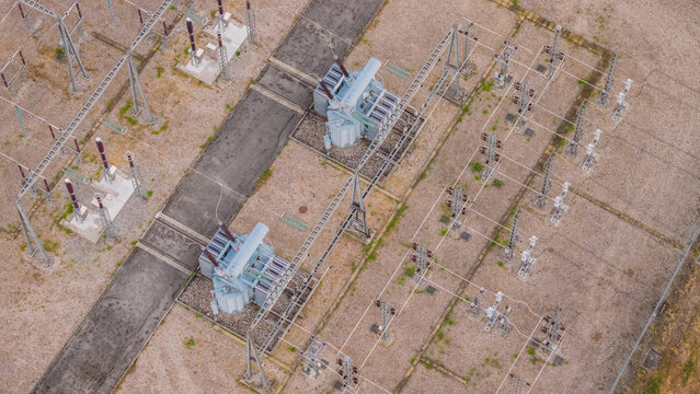 Aerial view of high-voltage power transformers with cooling radiators and transmission equipment inside an electrical substation in Valence, Auvergne-Rhone-Alpes, France.