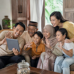 Fototapeta premium Happy multi-generation Asian family waving hands during video call on digital tablet at home