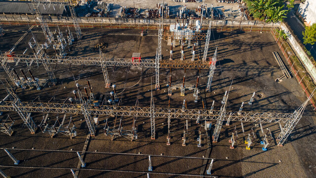 Aerial view of an electrical substation with metal structures, transformers, and power lines in Purwokerto, Central Java, Indonesia.