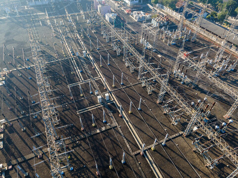 Aerial view of an electrical substation featuring complex metal power structures, high-voltage lines, and industrial equipment arranged on a gravel ground in Purwokerto, Central Java, Indonesia.