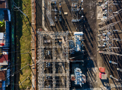 Aerial view of an electrical substation with metal power structures, transformers, and cables in Purwokerto, Central Java, Indonesia.