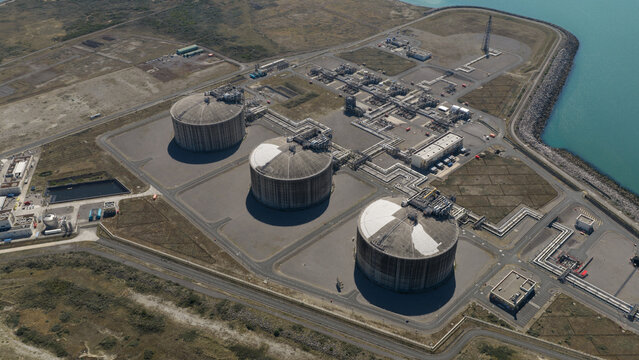 Aerial view of Dunkirk LNG Terminal featuring three large storage tanks and industrial infrastructure situated along the coast in Loon-Plage, Hauts-de-France, France.