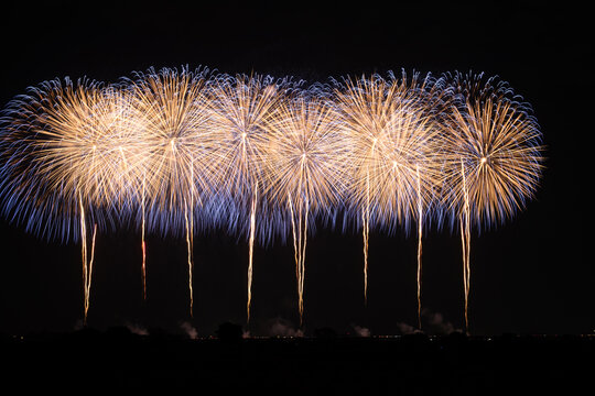 Eight giant shakudama fireworks bursting simultaneously in a dazzling night sky display at a Japanese fireworks festival