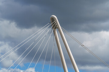 Fototapeta premium Modern architectural cable-stayed bridge pylon standing tall against a dramatic cloudy sky symbolizing engineering progress.