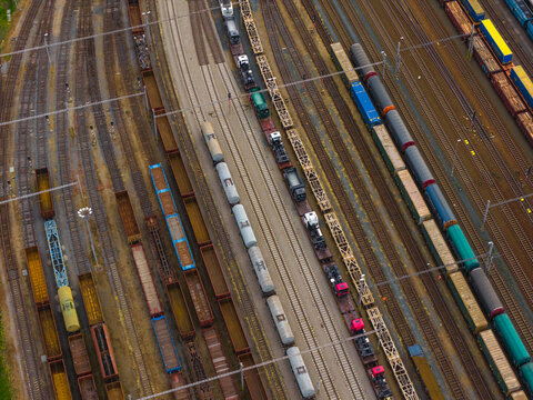 Aerial view of a busy railway yard featuring numerous freight trains with cargo cars and tankers parked on parallel tracks in Breclav, South Moravian Region, Czechia.