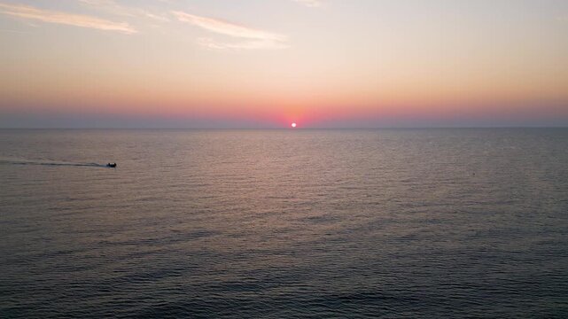 Small Boat Sailing in Calm Sea Water at Golden Sunrise Sunset