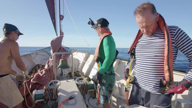 Crew work with the sails on the big expeditional sailing vessel moving in the Atlantic Ocean