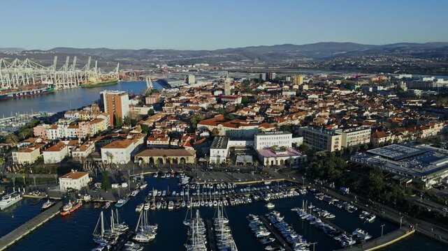 View of Kopers waterfront with boats in marina and city buildings along the shore under bright sky.