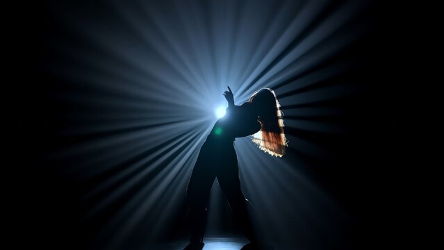 Silhouette of a female dancer performing on a dark stage, back lit by dramatic volumetric light rays with copy space. Concepts related to dance, self discovery, album covers, singles, or podcasts