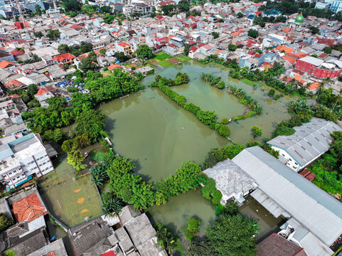Aerial view of flooded school grounds of SDN Kembangan Utara 2 PT3 PG surrounded by dense urban housing and rooftops in Kecamatan Kembangan, Daerah Khusus Ibukota, Indonesia.