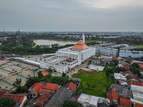 Aerial view of Masjid Raya BSD Baitul Mukhtar with its tiered orange roof, surrounded by residential houses with red-tiled roofs and a nearby lake in Kecamatan Pagedangan, Banten, Indonesia.