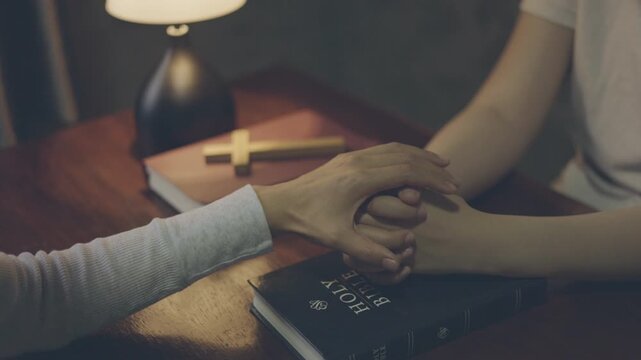 Two people praying together while holding hands, showing faith, trust, hope, love, peace, and unity.