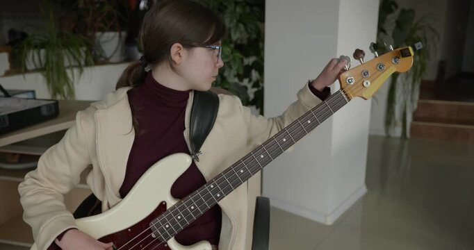 Musician Girl Play Bass Guitar at Home. Young Female Playing Music. 4K 10-bit