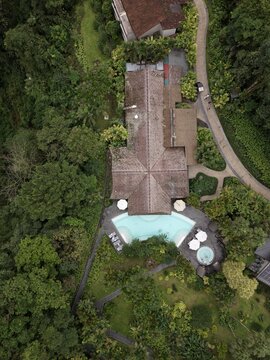 Aerial view of a resort building with a swimming pool and hot tub surrounded by lush tropical forest in Alajuela Province, Costa Rica.