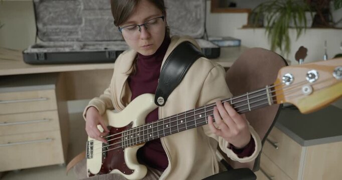 Musician Girl Play Bass Guitar at Home. Young Female Playing Music. 4K 10-bit