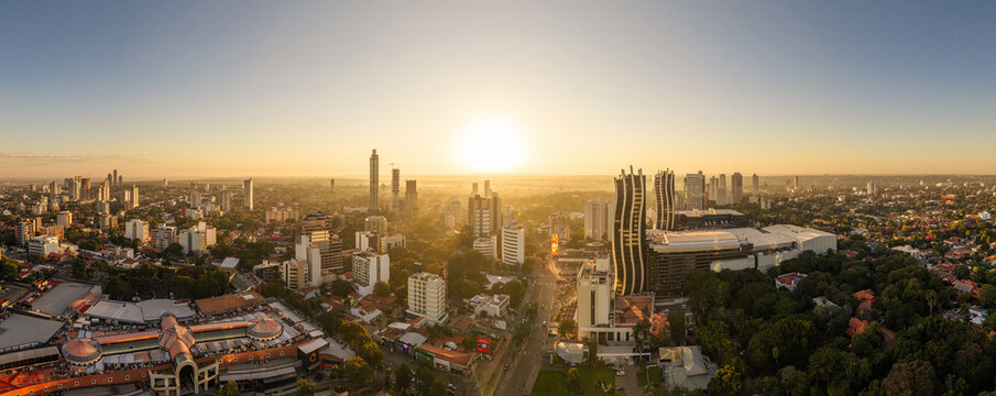 Aerial view of World Trade Center Asuncion surrounded by modern skyscrapers, lush urban greenery, and city streets during a golden sunset in Asuncion, Asuncion, Paraguay.