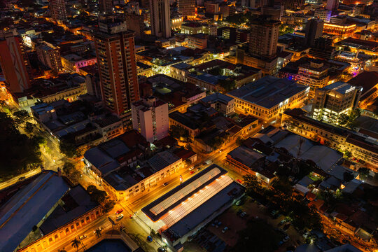 Aerial view of the illuminated cityscape of Asuncion at night, featuring dense urban architecture, glowing street lights, and a prominent central market building in Asuncion, Asuncion, Paraguay.