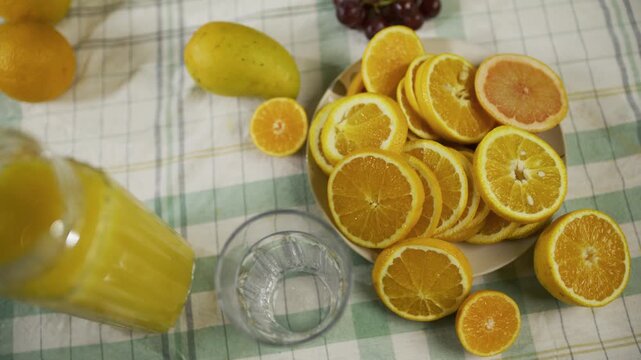 High, slow motion shot of pitcher pouring juice into glass near orange slices