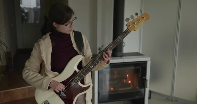 Musician Girl Play Bass Guitar at Home. Young Female Playing Music. 4K 10-bit