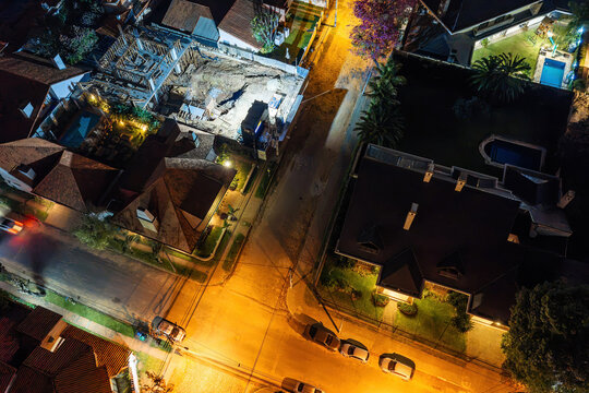 Aerial view of Las Lomas residential neighborhood at night with illuminated streets, houses with swimming pools, and construction site in Asuncion, Asuncion, Paraguay.