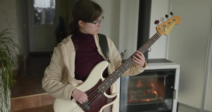 Musician Girl Play Bass Guitar at Home. Young Female Playing Music. 4K 10-bit